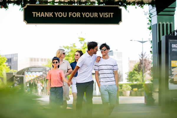 Bezoekers wandelen in de buitenlucht door Designer Outlet Roermond tijdens een zonnige dag.