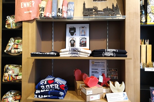 Een houten winkelrek met T-shirts, kaarsen, souvenirs en streekproducten.