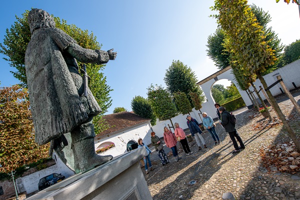 Groep staat voor een standbeeld in Thorn luisterend naar de uitleg van de gids.